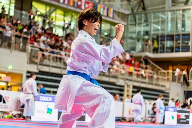 A person in a white uniform with a blue beltDescription automatically generated
